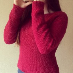 Teenage girl with long hair drinking from a mug and wearing a long sleeved, body hugging seed stitch cropped jumper with round neck